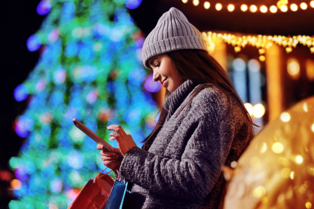 istock Woman texting on her mobile phone against decorated Christmas tree 1429726993