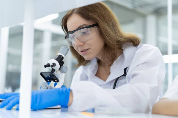istock Woman doctor looking through microscope doing analysis for germs and bacteria of test sample in the laboratory. Female scientist working with biotechnology research with microscope 1429729536
