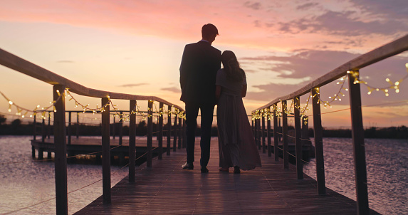 Couple in silhouette after wedding during sunset at beach in nature, bride and groom in celebration on summer holiday after marriage reception and freedom together at the ocean sea on vacation