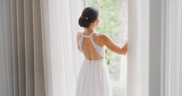istock Bride at window before wedding celebration, marriage and reception from the back. Elegant beauty of a young woman in bridal fashion dress getting married for special, happy and romantic event 1429730655