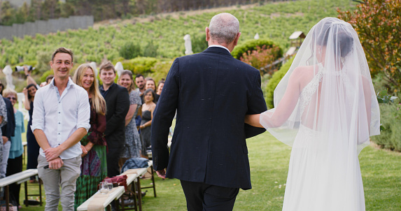Wedding, family and love with a father walking his daughter down the aisle as a bride on her marriage day. Ceremony, tradition and celebration event with a wife to be and her dad at an outdoor venue