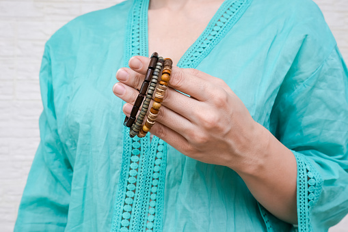 Unrecognized woman in ethnic clothes showing hand made bracelets with wooden beads on her hand.