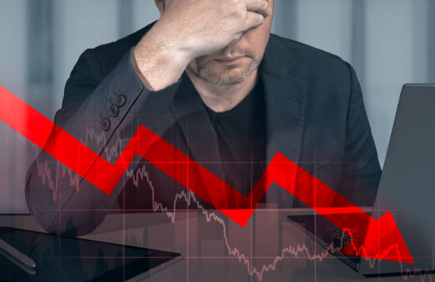 businessman holding hands on head looking at graph of declining profit. businessman looking up at chart that indicates falling dollar. graphs representing stock market crash caused - moving down dollar decline graph imagens e fotografias de stock