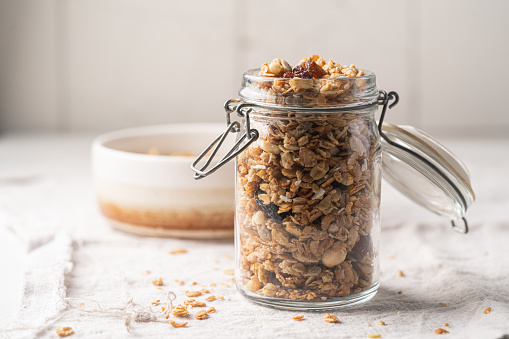 Delicious homemade granola in glass jar on white background. Breakfast. Healthy food sweet dessert snack. Diet nutrition concept. Vegetarian food.