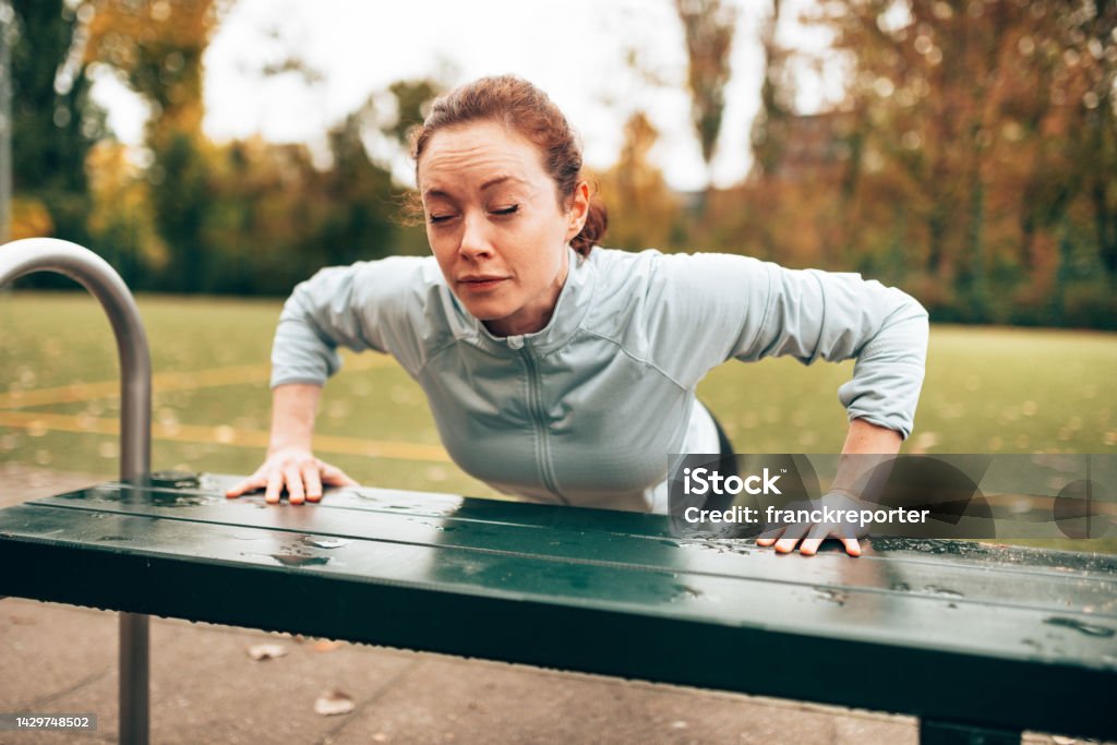 sportive woman doing pushups on the park 20-24 Years Stock Photo
