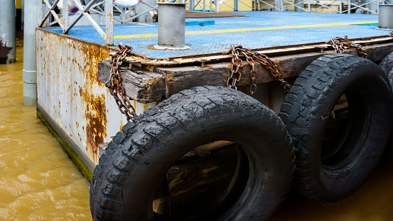 neumático de coche con una cadena de metal en un viejo muelle de hormigón del mar, neumáticos de camión viejos en el muelle.parachoques de neumáticos photo