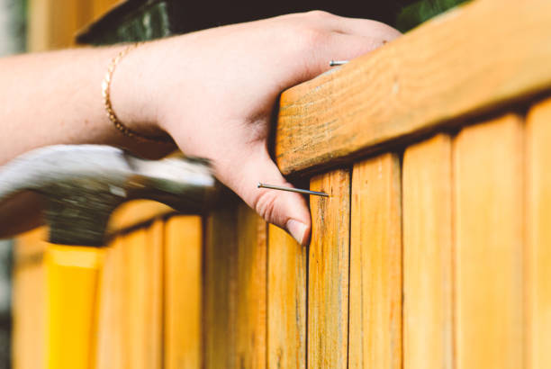 Man renovating wooden fence