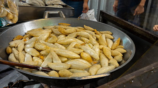 Fried fish balls with Rugby shape in a pan with boiling oil with traditional asian street food in the hot oil on market at Thailand