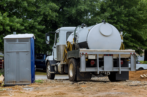 A septic vacuum truck is being used to clean portable restrooms the sewer pumping machine