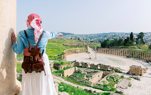 Jerash - jordan. travel tourism holiday background -young girl with hat standing pointing to Ancient Roman city of Gerasa of Antiquity, Jerash