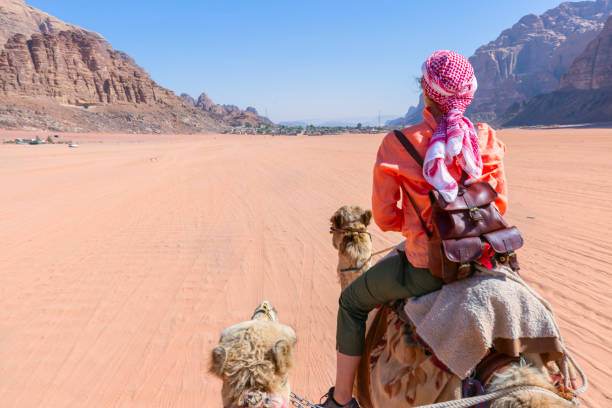 schöne junge touristin in weißem kleid reitet auf einem kamel in der wüste wadi rum, jordanien - jordan camel wadi rum arabia stock-fotos und bilder