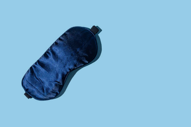 istock Dark blue sleeping mask on light blue background with copy space. Minimal concept of rest, quality of sleep, good night, insomnia, relaxation. Flat lay 1429781224
