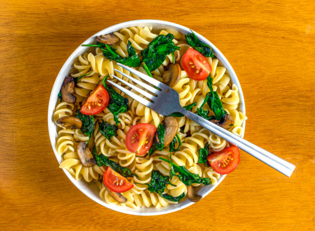 rotini pasta salad consisting of sauteed mushrooms and spinach with tomatoes,