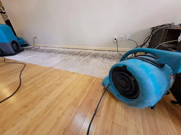 Photo of Air mover and a dehumidifier in place to dry a floor after a pipe break.