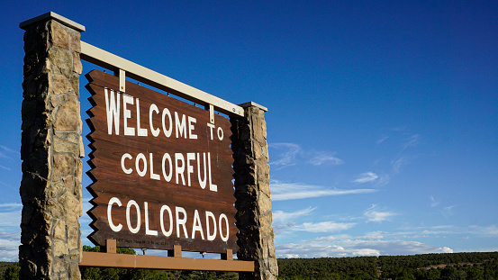 A wooden sign on the border of Colorado welcoming people into the state.