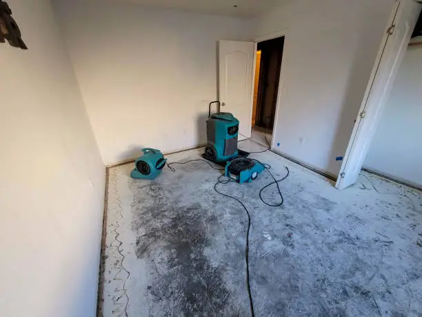 Water Damaged bedroom with carpet removed and air movers with a dehumidifier for drying