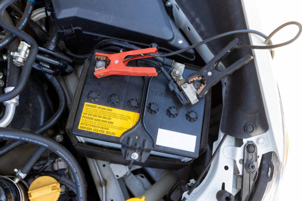 Set of heavy-duty copper battery jumper cables with red and black insulated handles coiled on a white background.