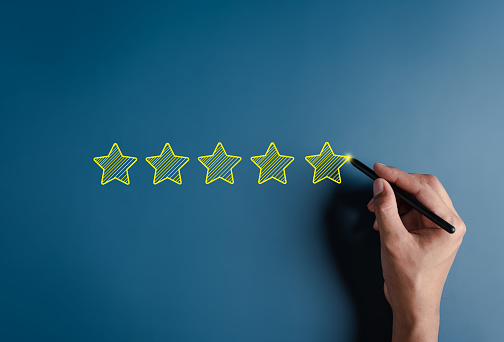 Hand writing five stars for customer feedback and evaluation in experience service and product. Excellent rating. User give rating, good business network score.