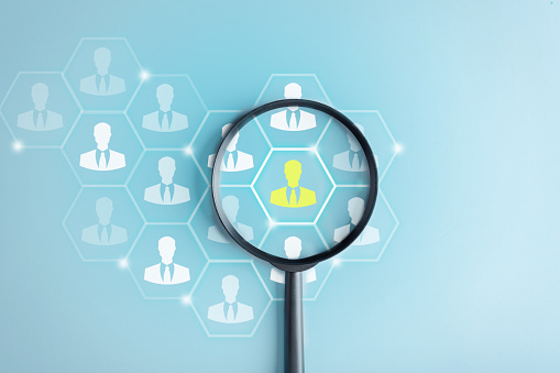 HRM or Human Resource Management, Magnifier glass focus to manager icon which is among staff icons for human development recruitment leadership and customer target group concept.