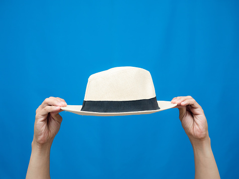 Hand hold beach hat blue background isolated