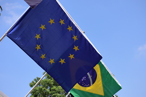 Brazilian and European, European Union flags placed side by side, with blue sky background. High quality photo