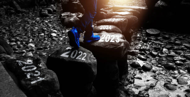 menino cruzando degraus com o ano novo número 2022 a 2023 e 2024 - stepping stone stone stepping footpath - fotografias e filmes do acervo