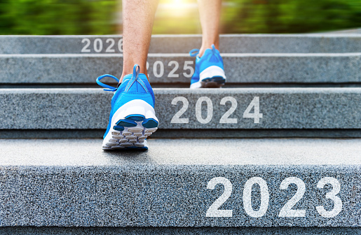 Sección baja del hombre subiendo escaleras con número de año nuevo 2023, 2024, 2025 y 2026 photo
