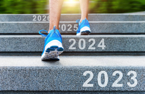 Low section of man climbing up stairs with new year number 2023, 2024, 2025 and 2026 stock photo