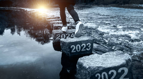 mulher cruzando degraus com número de ano novo 2023, 2024 e 2025 - stepping stone stone stepping footpath - fotografias e filmes do acervo