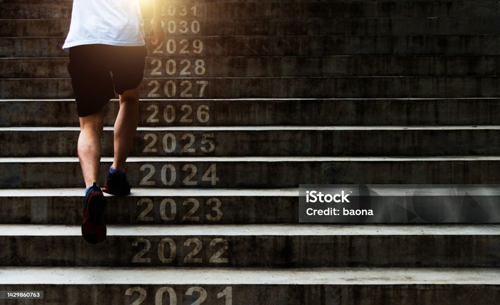 Man running up outdoor stairs with new year number 2022, 2023, 2024 to 2031 2023 Stock Photo