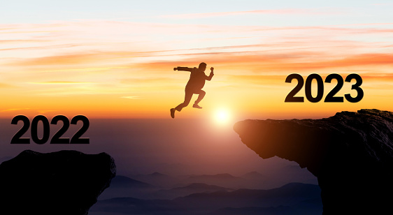 Businessman jumping from 2022 cliff to 2023