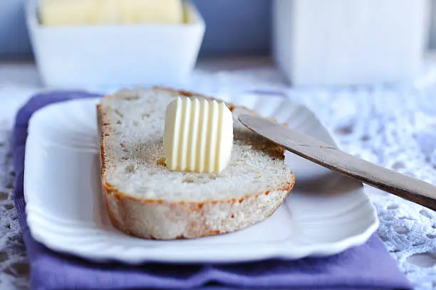 Photo of Bread and butter with a wooden knife for breakfast