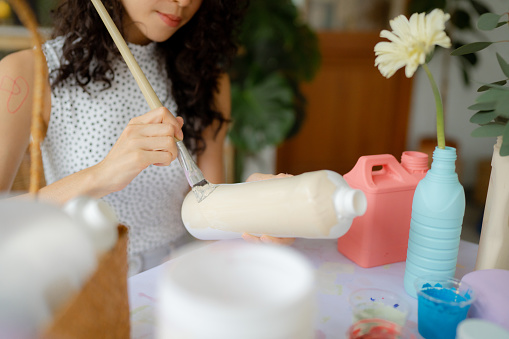 Asian woman pans flower vases out of unused plastic.