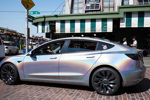 Seattle, USA - Aug 31st, 2022: Pike Place Market late in the day as a Tesla passes by.