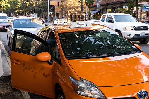 Seattle, USA - Sep 26, 2022: Late in the day in Belltown, an old taxi cab with a piece of paper that says UBER taped over the light.