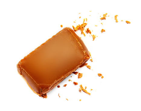 Sweet melted caramel with sauce flowing on caramel candy isolated on white background. Top view. Flat lay