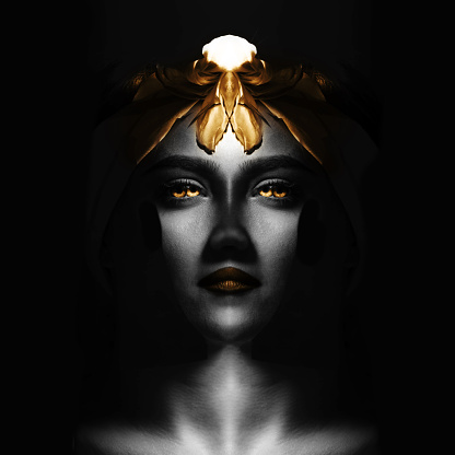Abstract, fine art, sci-fi concept. Abstract and futuristic looking woman portrait. Alien or extraterrestrial looking model with golden hair, eyes and lips looking calmly at camera