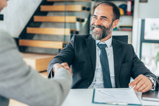 Handshake for the new agreement Senior businessmen shaking hands in the office. Cheerful Businessmen greeting each other for new partnership. Signing new agreement in modern office Financial Advisor stock pictures, royalty-free photos & images