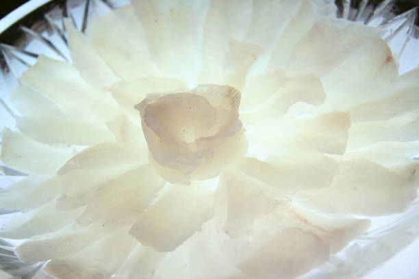 Filefish thinly sliced sashimi in a glass bowl. Lighting from below creates a transparent image.