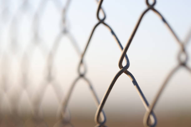Closeup of chain link fence. Mesh netting on gray background. Prison and freedom
