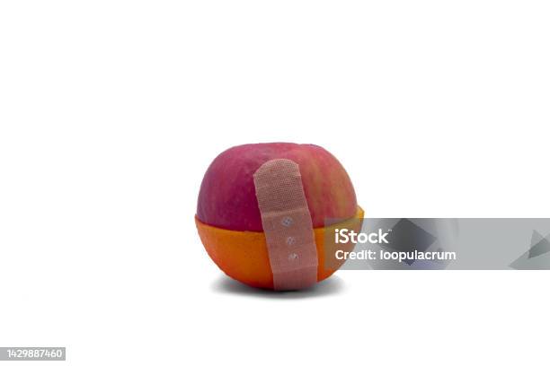 Band Aid Holding Half Of Orange And Apple On White Background With Clipping Path Stock Photo - Download Image Now