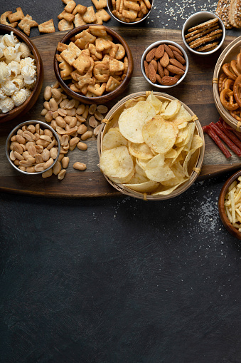 Assortment of salty snacks on dark background. Party food concept. Top view, copy space