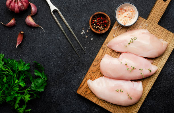 raw chicken breast fillet, meat on cutting board prepared for cooking with garlic, thyme, spices and pepper. black kitchen table, top view - garlic chicken breast raw chicken imagens e fotografias de stock