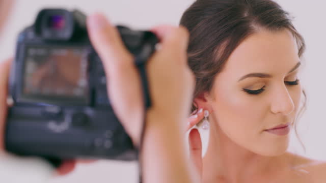 Bride, beauty and photographer at wedding pictures with woman posing for camera at event celebration ceremony. Creative bridal makeup cosmetics and fashion marriage photoshoot with attractive woman