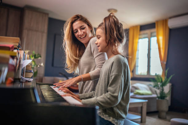 mutter und tochter spielen klavier im wohnzimmer - practicing piano child playing stock-fotos und bilder