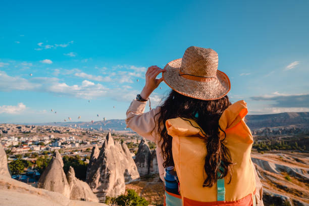 ragazza fotografa viaggiatrice che guarda le mongolfiere durante l'alba in cappadocia nevsehir , turchia - hot air balloon landscape sunrise mountain foto e immagini stock