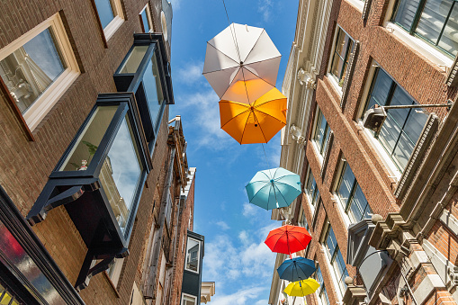 Colorful umbrellas in the air against blue sky with clouds