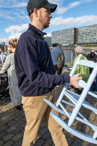 Copenhagen Denmark Sept 11, 2022  A man at a flea market near the Islands Brygge landmark carries a baby rocking chair.