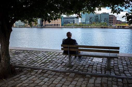 Copenhagen Denmark Sept 11, 2022  A man sits alone on a bench in the Copenhagen harbor.