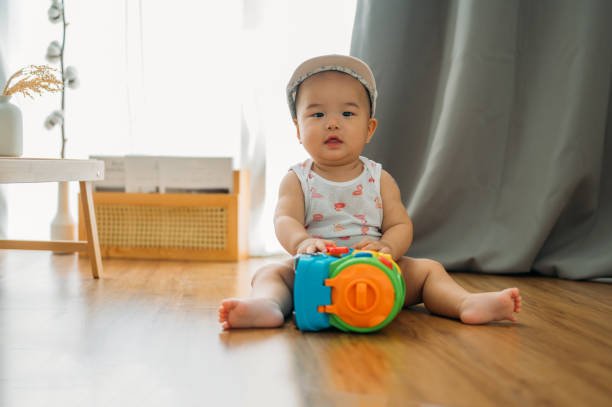 A Cute 9 month Asian baby sitting on floor, playing with toys stock photo